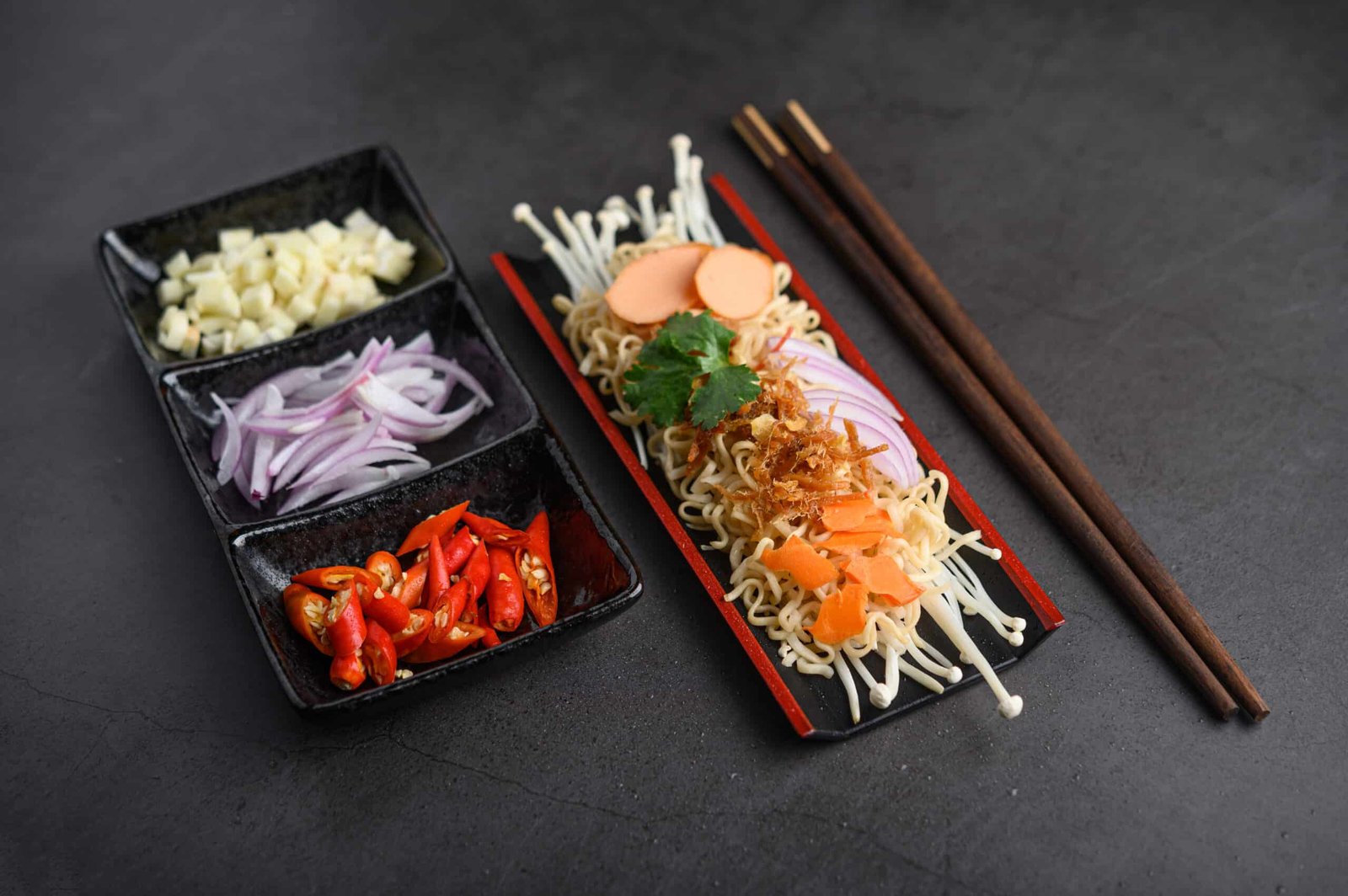 konjac japanese food on two platters nad two chosticks on a black surface