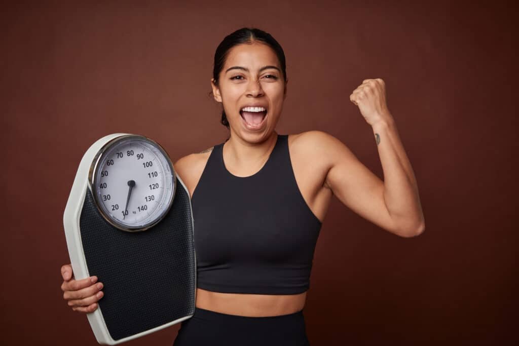 Young fitness woman measuring progress with a scale for healthy living after eating konjac knots.