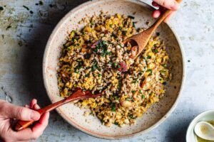 A bowl of fried konjac rice keto with scrambled eggs, colorful vegetables and garnished with fresh chives.