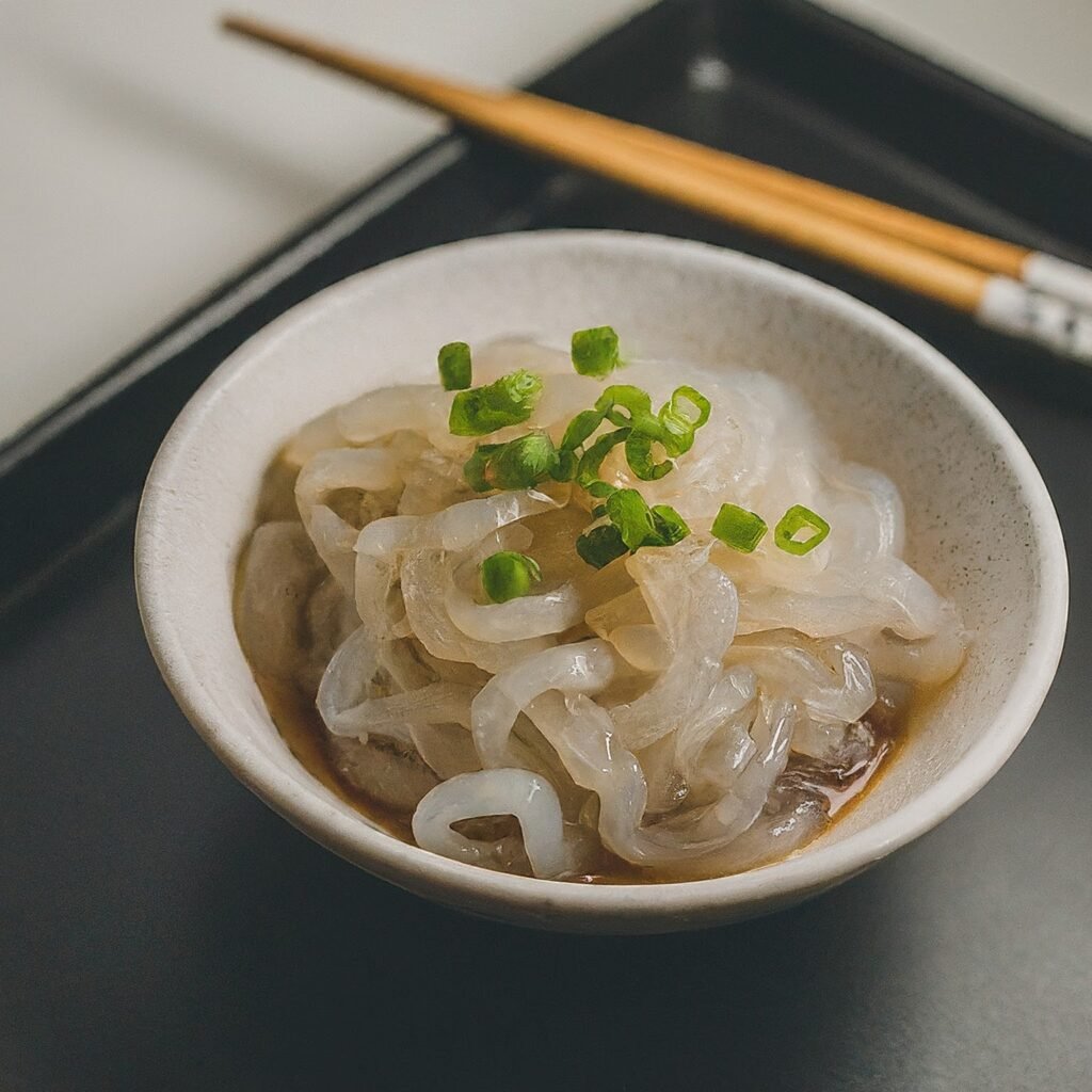 A bowl of shirataki noodles, a popular low-calorie food, topped with green onions and a light sauce.