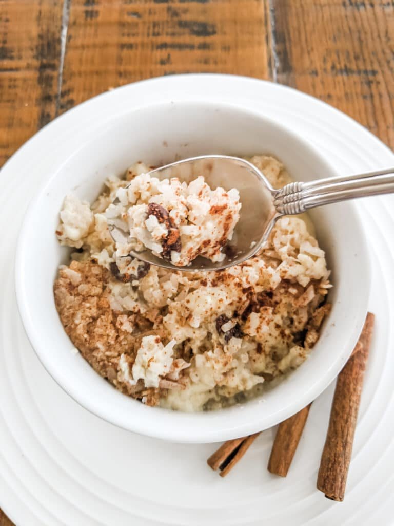 One of konjac rice recipes - creamy rice pudding with raisins, sprinkled with cinnamon, served in a white bowl.