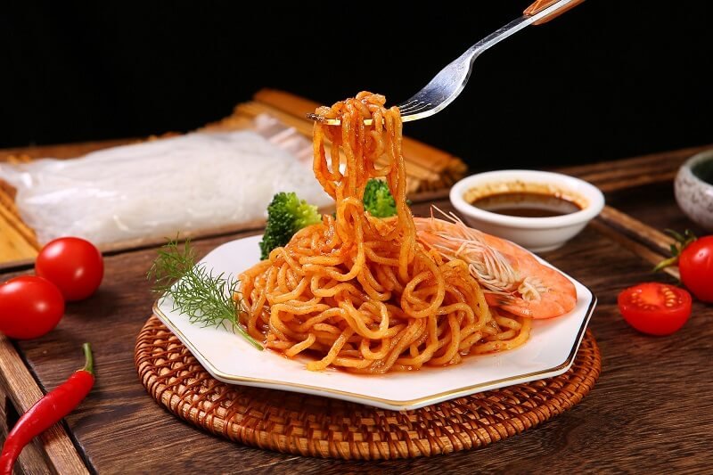 A plate of appetizing konjac noodles topped with shrimp, broccoli, and a flavorful sauce, ready to be enjoyed with a fork for a low FODMAP dinner.