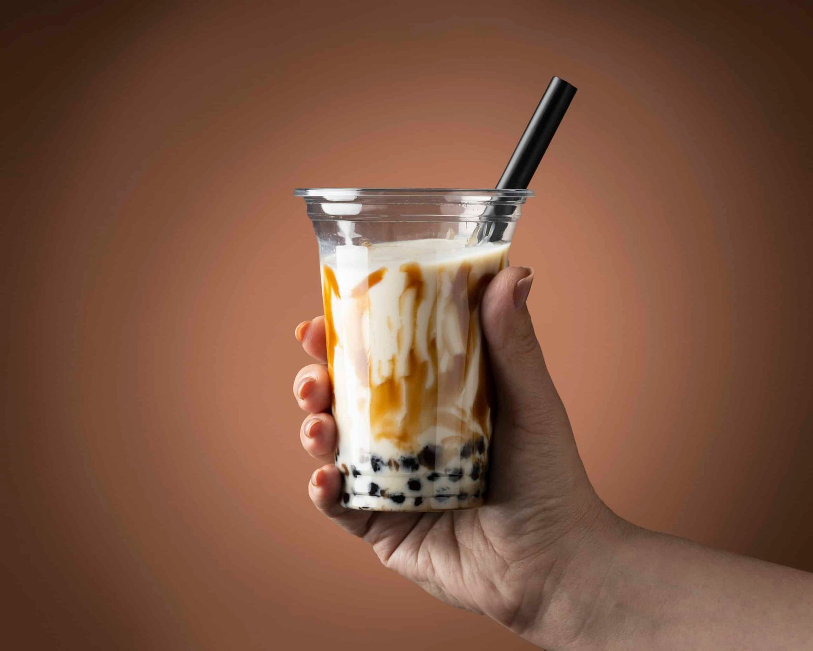 a hand holding a konjac boba infront of a brown background