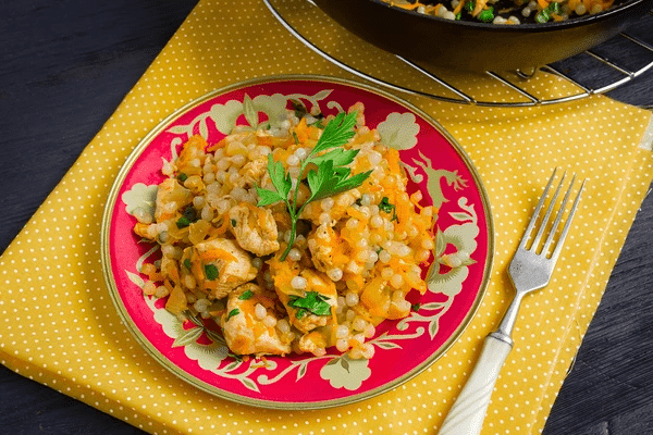 One of konjac rice recipes - a healthy and hearty rice dish featuring couscous, chicken, and vegetables, served on a vibrant plate.