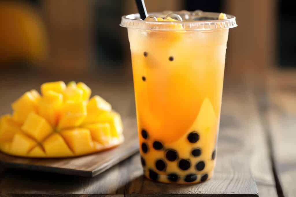 Mango flavored bubble tea with popping Konjac boba on a warm summer day. Refreshing drink in a glass with a straw. Citrus flavor from the mango sweet and fruity aroma.