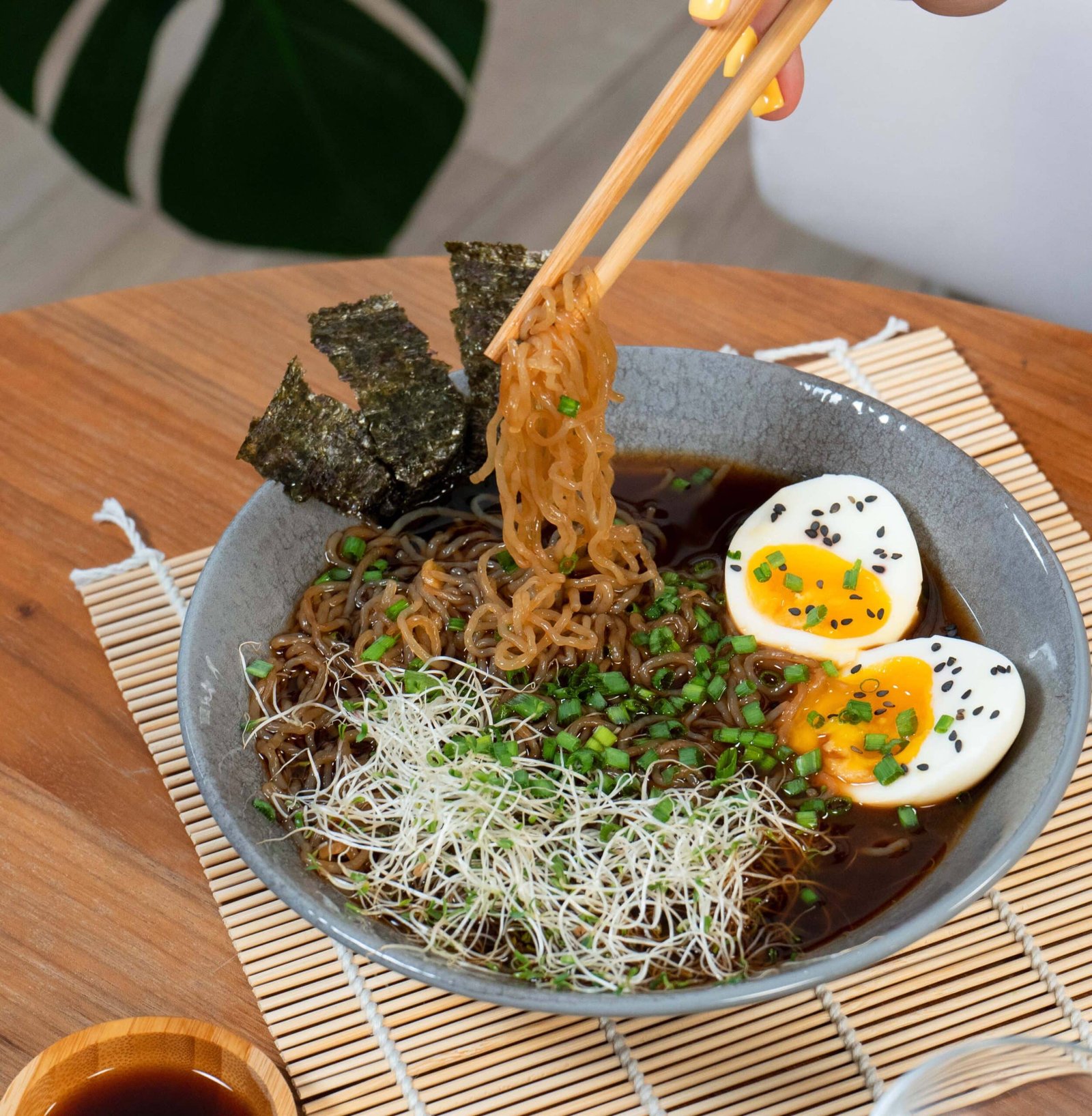 A bowl of steaming ramen with konjac noodles, soft-boiled egg, nori, scallions, and sprouts for a low FODMAP dinner.